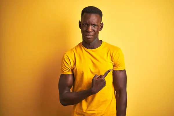 孤立した黄色の背景の上に立つカジュアルなTシャツを着た若いアフリカ系アメリカ人男性は 人差し指で心配と緊張を脇に置き 心配し 驚いた表情を — ストック写真