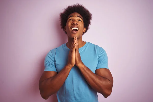 非洲裔美国男子 一个非洲头发 穿着蓝色T恤站在孤立的粉红色背景乞讨和祈祷与双手一起与希望表达在脸上非常情绪化和担心 请求宽恕 宗教概念 — 图库照片
