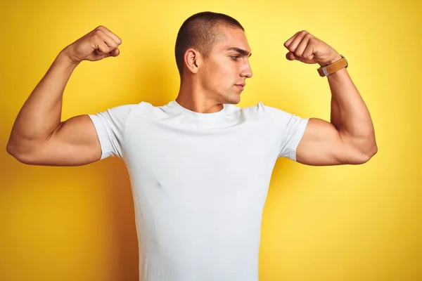 年轻的白种人男子穿着休闲的白色T恤在黄色孤立的背景显示手臂肌肉微笑自豪 健身理念 — 图库照片