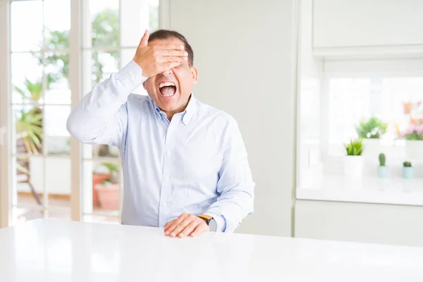 Uomo Mezza Età Seduto Casa Sorridente Ridente Con Mano Sul — Foto Stock