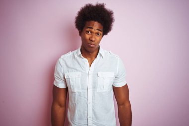 Beyaz gömlek giyen afro saçlı genç Amerikalı adam izole pembe arka plan üzerinde ayakta depresif ve sıkıntı için endişe, kızgın ve korkmuş ağlıyor. Hüzünlü ifade.