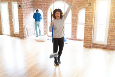 Kıvırcık saçlı orta yaşlı kadın ev usin temizlik çalışıyor