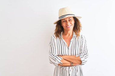 Izole beyaz arka plan üzerinde çizgili elbise ve şapka giyen orta yaş iş kadını mutlu yüz kameraya bakarak çapraz kolları ile gülümseyerek. Pozitif kişi.