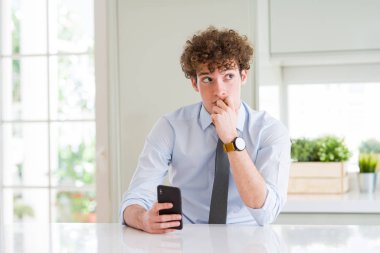 Ofiste akıllı telefon kullanan genç iş adamı ciddi yüz soru hakkında düşünme, çok karışık fikir