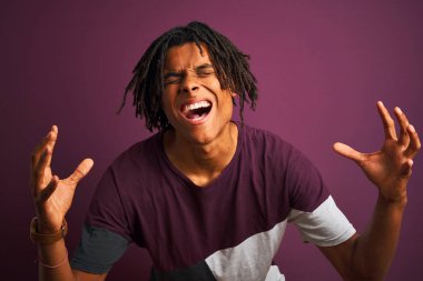 Dreadlocks rahat t-shirt giyen afro adam izole mor arka plan üzerinde ayakta silah kaldırdı ve kapalı gözleri ile başarı için deli ve deli kutluyor heyecanlı çığlık. Kazanan kavramı