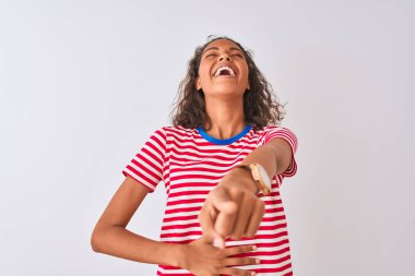 Kırmızı çizgili t-shirt giyen genç brezilyalı kadın izole beyaz arka plan üzerinde duran size gülüyor, vücut üzerinde el ile kameraya parmak işaret, utanç ifadesi