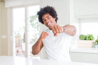 Evde oturan rahat beyaz tişört giyen genç Afro-Amerikan adam yumruk yumruğa dövüşmek, saldırgan ve öfkeli saldırı, tehdit ve şiddet