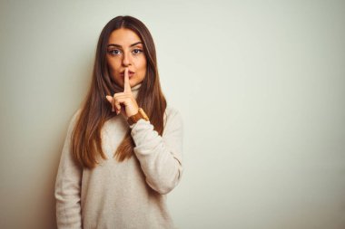 Young beautiful woman wearing winter turtleneck sweater over isolated white background asking to be quiet with finger on lips. Silence and secret concept.