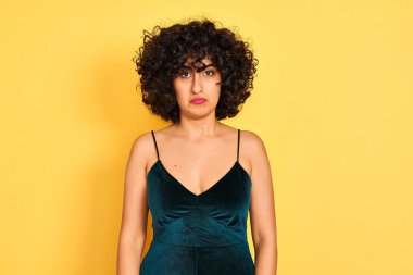 Kıvırcık saçlı genç arap kadın izole sarı arka plan üzerinde zarif elbise giyen depresif ve sıkıntı için endişe, kızgın ve korkmuş ağlıyor. Hüzünlü ifade.