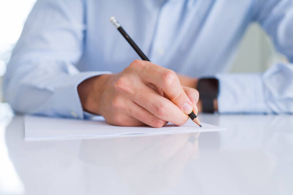 Close up of man hands writing using a pencil on paper over white