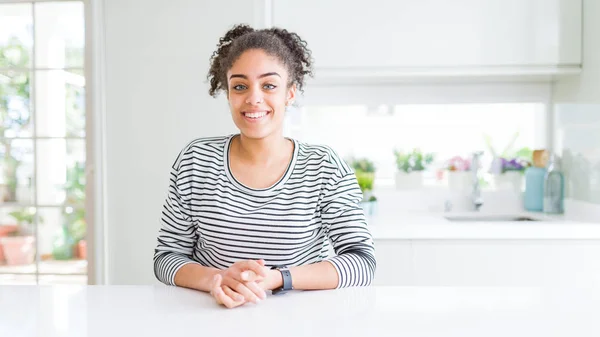 Beautiful african american woman with afro hair wearing casual striped sweater with hands together and crossed fingers smiling relaxed and cheerful. Success and optimistic