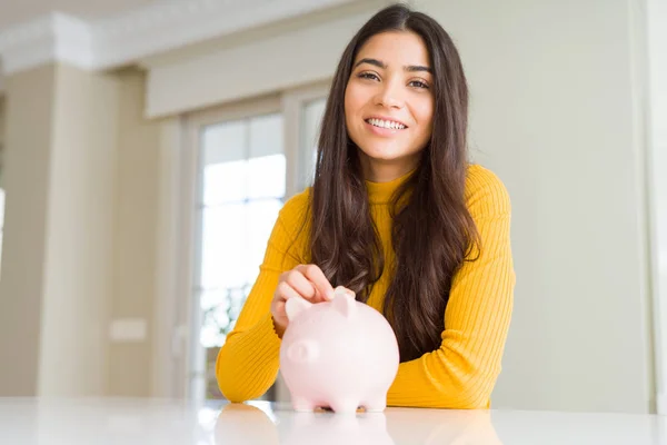 Close up de mulher sorrindo colocando uma moeda dentro do banco porquinho como em — Fotografia de Stock