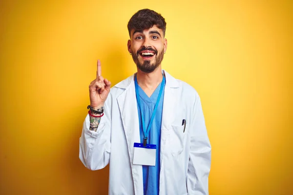 Junger Arzt Mit Tätowiertem Ausweis Der Vor Isoliertem Gelben Hintergrund — Stockfoto