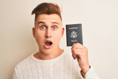 Izole beyaz arka plan üzerinde ABD pasaportu tutan genç yakışıklı adam sürpriz bir yüz ile şok korkmuş, korku ifade korku ve heyecanlı
