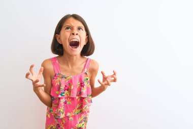 Genç güzel çocuk kız izole beyaz arka plan deli ve deli bağırarak ve agresif ifade ve kollar kaldırdı ile bağırıyor üzerinde duran pembe çiçekli elbise giyiyor. Hayal kırıklığı kavramı.
