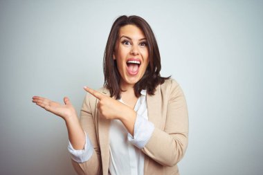 Genç güzel şık iş kadını üzerinden hayran ve el ile sunulması ve parmak ile işaret ederken kameraya gülümseyen izole arka plan.