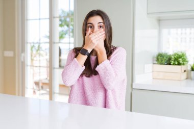 Pembe kazak giyen güzel genç kadın hata için elleri ile ağız kapsayan şok. Gizli kavram.