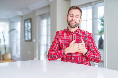 Renkli gömlek giyen yakışıklı adam yüzünde kapalı gözler ve minnettar jest ile göğsünde eller ile gülümsüyor. Sağlık konsepti.