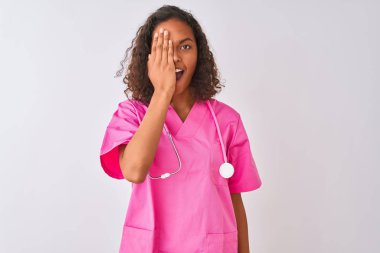 Genç Brezilyalı hemşire kadın stetoskop giyen izole beyaz arka plan üzerinde bir göz el, yüzünde kendine güvenen gülümseme ve sürpriz duygu kapsayan ayakta.