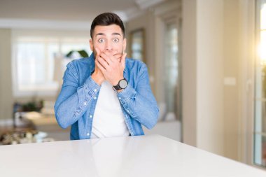 Evde genç yakışıklı adam hata için elleri ile ağız kapsayan şok. Gizli kavram.