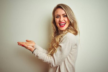 Izole beyaz arka plan üzerinde kış balıkçı yaka kazak giyen güzel kadın kopya alanı gösteren elleri açık avuç içi ile bir kenara işaret, reklam gülümseyerek mutlu gülümseyen