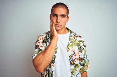 Tatilde genç yakışıklı adam beyaz arka plan üzerinde Diş ağrısı veya diş üzerinde diş hastalığı nedeniyle ağrılı ifade ile el ile ağız dokunmadan Hawaii gömlek giyiyor. Diş hekimi konsepti.