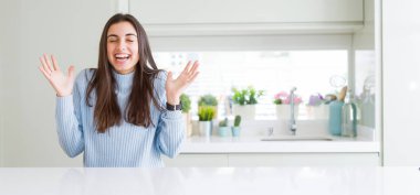 Güzel genç kadının evde beyaz masada oturan geniş açı resmi silah ile başarı için deli ve deli kutluyor ve heyecanlı çığlık kapalı gözleri kaldırdı. Kazanan kavramı