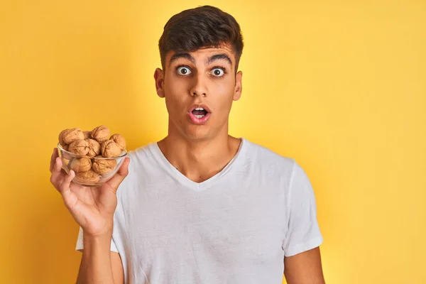 Young Indian Man Holding Bowl Walnuts Standing Isolated Yellow Background — Stock Photo, Image