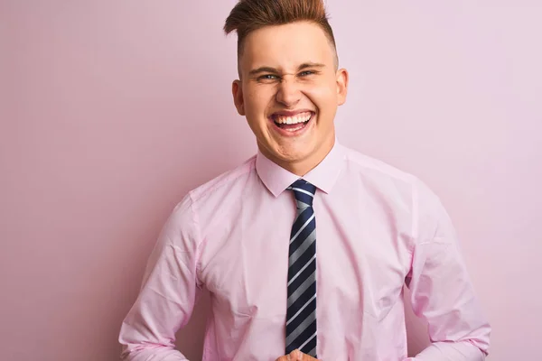 年轻的英俊商人穿着衬衫和领带站在孤立的粉红色背景微笑和笑硬大声 因为有趣的疯狂笑话与手在身体上 — 图库照片