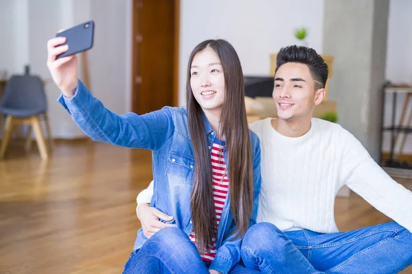Молода азіатська пара посміхається, роблячи селфі фото зі смартфоном — стокове фото