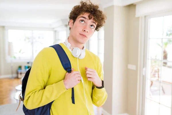 年轻学生男子戴着耳机和背包认真面对思考问题 想法很困惑 — 图库照片