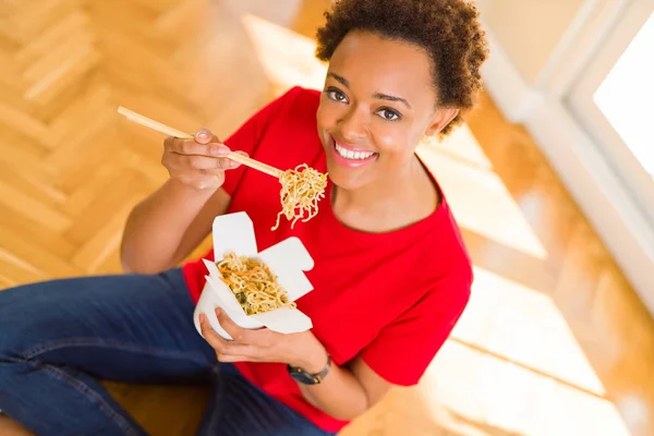 Hermosa joven afroamericana mujer comiendo fideos usando choo — Foto de Stock