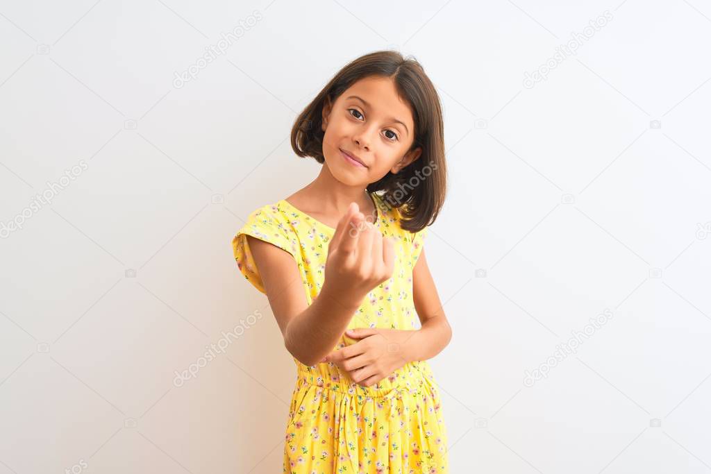 Young beautiful child girl wearing yellow floral dress standing over isolated white background Beckoning come here gesture with hand inviting welcoming happy and smiling