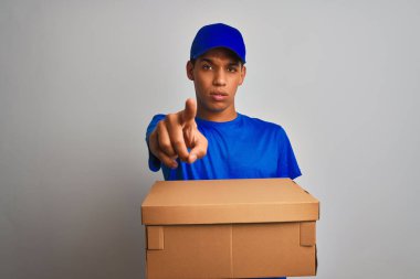 Genç yakışıklı arap teslimat adam kamera ve size parmak ile işaret izole beyaz arka plan üzerinde duran bir kutu tutan, el işareti, önden olumlu ve kendinden emin jest