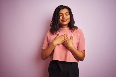 Izole pembe arka plan üzerinde genç güzel transseksüel transseksüel zarif kadın kapalı gözleri ve yüzünde minnettar jest ile göğüs elleri ile gülümseyerek. Sağlık kavramı.