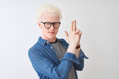 Genç albino sarışın adam izole beyaz arka plan üzerinde denim gömlek ve gözlük giyen el hareketi ile sembolik silah Holding, çekim silah öldürme oynarken, kızgın yüz