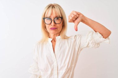 Kızgın yüzlü izole beyaz arka plan üzerinde duran gömlek ve gözlük takan orta yaş iş kadını, başparmak aşağı ile sevmediğimi gösteren negatif işaret, ret kavramı