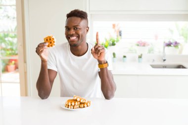 Tatlı Belçikalı Waffle yiyen Afrikalı Amerikan adam bir fikir veya soru mutlu yüz, bir numara ile parmak işaret ile şaşırdı