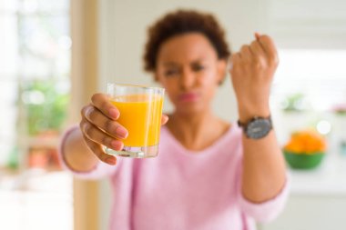 Ev rahatsız ve hayal kırıklığı ile öfke, çılgın ve yükseltilmiş eliyle diye bağıran öfke kavramı bağırarak, genç Afro-Amerikan kadın driking portakal suyu