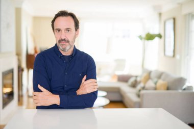 Evde yakışıklı orta yaş adam şüpheci ve sinir, kesişen silah ile yüz üzerinde ifade onaylamaz. Negatif kişi.