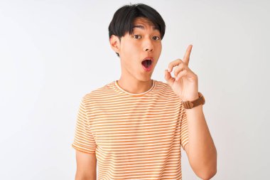 Genç Çinli adam rahat çizgili t-shirt izole beyaz arka plan üzerinde başarılı bir fikir ile parmak işaret üzerinde duran giyiyor. Çıktı ve mutlu. Bir numara.