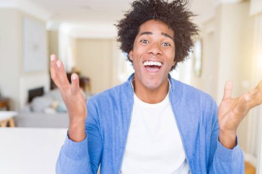 Afrika kökenli Amerikalı adam evde çılgın ve başarı için hayran kaldırdı Kollarını açarak kutluyor ve heyecanlı çığlık gözleri açık. Kazanan kavramı
