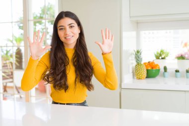 Genç güzel kadın evde gösterilen ve parmakları ile işaret beyaz masada kendinden emin ve mutlu gülümseyerek süre on numara.
