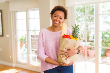 Kağıt torba dolu tutan genç güzel Afrikalı-Amerikalı kadın
