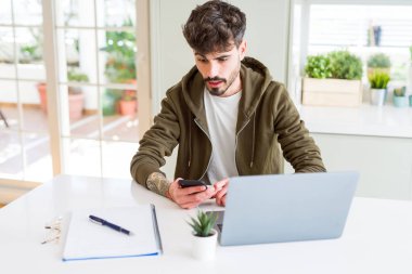 Akıllı telefon kullanan ve dizüstü bilgisayar eğitimi alan genç öğrenci sürpriz bir yüzle şokta korkmuş, korku ve korku ifadesi ile heyecanlı