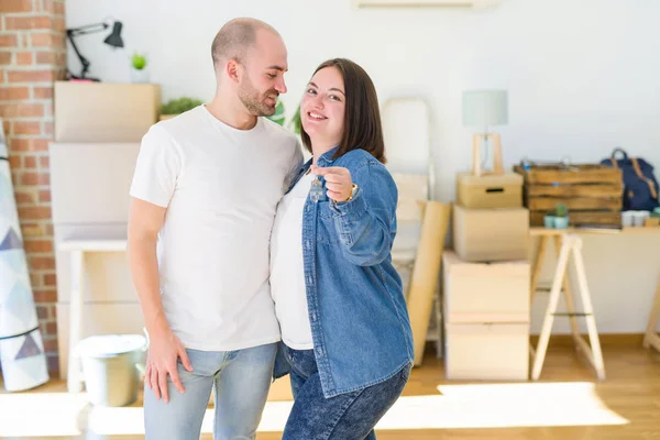 Νεαρό ζευγάρι χαμογελά πολύ χαρούμενος δείχνοντας τα κλειδιά του νέου σπιτιού, κινείται — Φωτογραφία Αρχείου