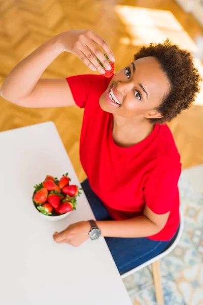 Gyönyörű fiatal afrikai-amerikai nő eszik friss piros szamóca, megta — Stock Fotó