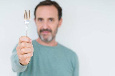 Üst düzey adam ciddi düşünme akıllı yüz üzerinde emin bir ifade ile izole arka plan üzerinde gümüş çatal tutan