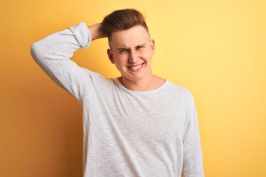 Izole sarı arka plan üzerinde duran beyaz rahat t-shirt giyen genç yakışıklı adam karıştırmayın ve soru hakkında merak ediyorum. Şüpheyle belirsiz, eliyle kafada düşünmek. Pensive kavramı.