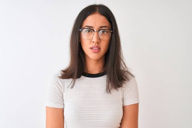 Çinli kadın yüzünde ciddi ifade ile izole beyaz arka plan üzerinde duran rahat t-shirt ve gözlük giyiyor. Kameraya basit ve doğal bir bakış.